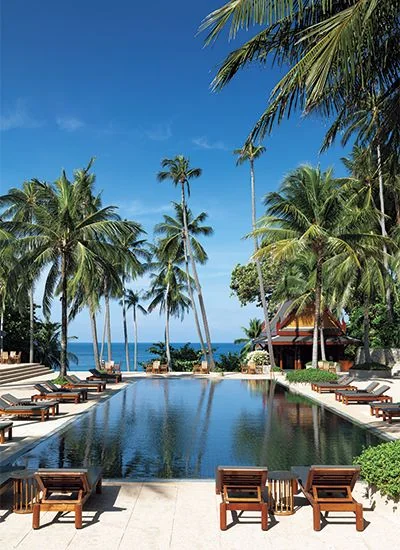 Amanpuri resort swimming pool surrounded by Thai pavilions and palm trees